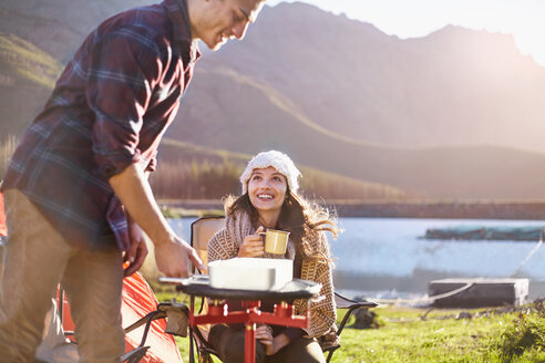 Junges Paar beim Camping, Kochen am Campingkocher am sonnigen Seeufer - CAIF05109