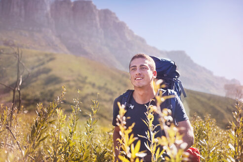 Junger Mann mit Rucksack beim Wandern im sonnigen Tal - CAIF05111
