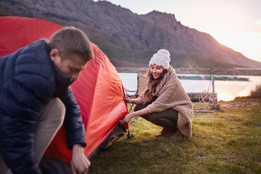 Junges Paar beim Zeltaufbau auf einem Campingplatz am See - CAIF05112