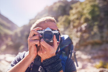 Young man hiking, photographing with camera - CAIF05120