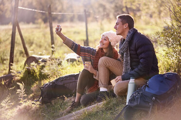 Young couple taking a break from hiking, taking selfie with camera phone - CAIF05128