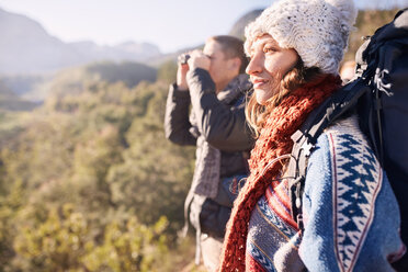 Young couple hiking, looking at sunny view with binoculars - CAIF05130