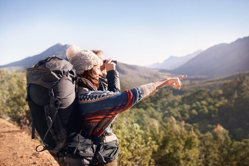 Young couple hiking, looking at sunny view with binoculars - CAIF05132