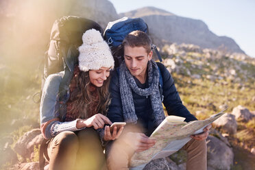 Young couple with backpacks hiking, resting and checking map and smart phone - CAIF05140