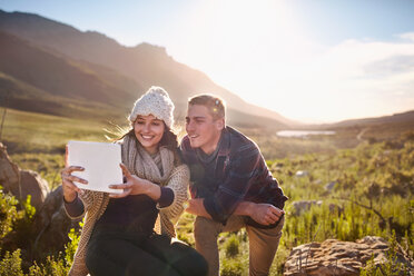 Young couple taking selfie with digital tablet camera in sunny valley - CAIF05147