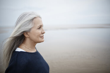 Pensive senior woman looking away on winter beach - CAIF05184