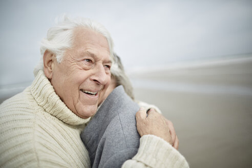 Zärtliches älteres Paar, das sich am Winterstrand umarmt - CAIF05185