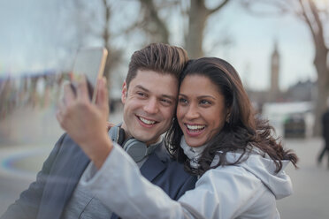 Smiling couple taking selfie with camera phone in urban park - CAIF05190