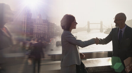 Silhouette Geschäftsleute schütteln sich die Hände auf einer sonnigen Brücke über die Themse, London, UK - CAIF05203