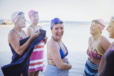 Porträt lächelnde weibliche Freiwasserschwimmerinnen, die sich mit Handtüchern im Meer abtrocknen - CAIF05218