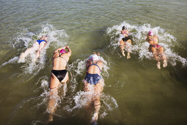 Blick von oben auf weibliche Freiwasserschwimmer, die im sonnigen Meer schwimmen - CAIF05223