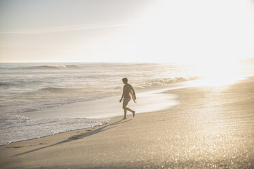 Silhouette woman walking on sunny summer ocean beach - CAIF05251
