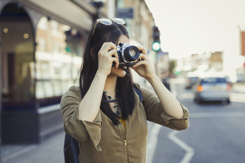 Junge weibliche Touristin beim Fotografieren mit der Kamera auf einer städtischen Straße - CAIF05268