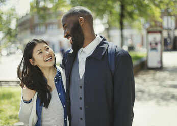 Affectionate couple laughing in sunny urban park - CAIF05285