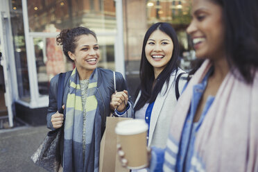 Lächelnde Freundinnen mit Einkaufstüten und Kaffee vor dem Geschäft - CAIF05299