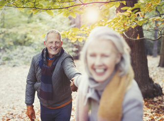 Verspieltes älteres Paar hält Hände im Herbstpark - CAIF05314