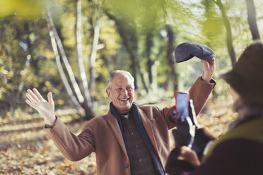Älterer Mann posiert für Frau mit Fotohandy im Herbstpark - CAIF05316