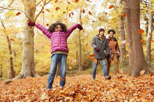 Verspieltes Mädchen wirft Herbstblätter im Wald - CAIF05321