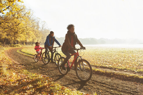 Verspielte junge Familie Fahrradfahren auf dem Weg in sonnigen Herbst Park - CAIF05326