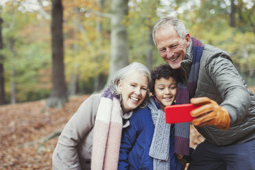 Großeltern und Enkel machen ein Selfie im Herbstwald - CAIF05327