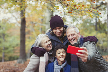 Mehrgenerationenfamilie macht Selfie mit Fotohandy im Herbstwald - CAIF05329