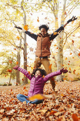 Verspielte Mutter und Tochter werfen Herbstblätter im Park - CAIF05335