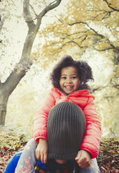 Portrait lächelnd Tochter zieht Strumpfmütze über Väter Kopf im Herbst Park - CAIF05336