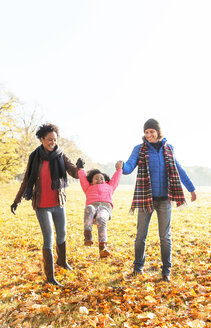 Eltern schaukeln Tochter im sonnigen Herbst Park - CAIF05337