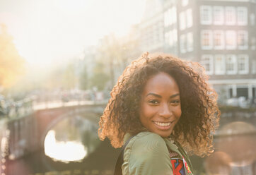 Porträt einer lächelnden jungen Frau entlang einer Gracht, Amsterdam - CAIF05360