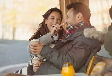 Verspieltes junges Paar mit Milchshake in einem Straßencafé - CAIF05365
