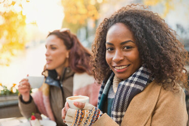 Portrait lächelnde junge Frau in warmer Kleidung trinkt Espresso in einem Straßencafé - CAIF05368