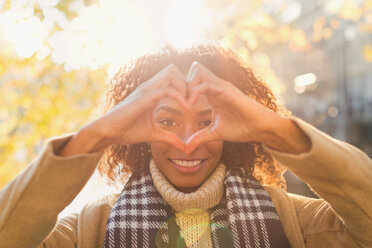 Portrait smiling young woman forming heart-shape with hands - CAIF05383