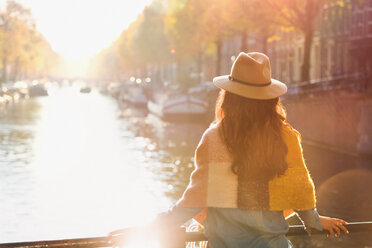 Frau mit Blick auf eine sonnige Grachtenlandschaft im Herbst, Amsterdam - CAIF05384