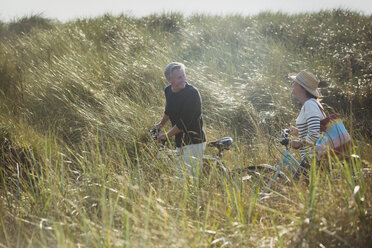 Älteres Paar zu Fuß Fahrräder in sonnigen Strand Gras - CAIF05391