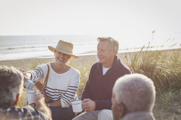 Ältere Paare trinken Kaffee am sonnigen Strand - CAIF05397