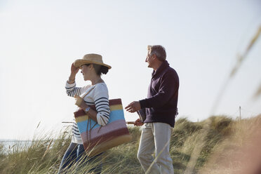 Älteres Paar spaziert auf sonnigem Strand Gras Weg - CAIF05398