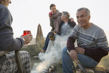 Ältere Paare trinken Wein und grillen am Strand - CAIF05402