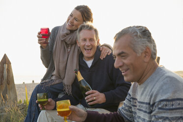 Verspielte reife Freunde trinken Champagner am Strand - CAIF05415