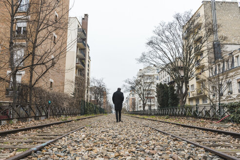 Frankreich, Paris, Rückenansicht eines Mannes, der entlang verlassener Eisenbahnschienen geht - AFVF00280