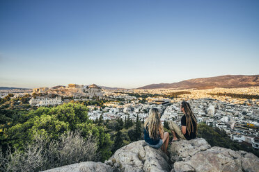 Paar sitzt auf Felsen mit Blick auf die Landschaft, Athen, Griechenland - CAIF05426