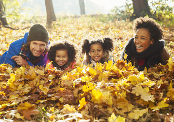 Porträt lächelnd junge Familie im Herbst Blätter in sonnigen Wäldern liegen - CAIF05438