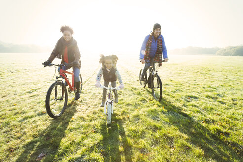 Portrait junge Familie Fahrradfahren in sonnigen Herbst Park Gras - CAIF05442