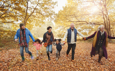 Verspielte Mehrgenerationenfamilie beim Laufen im Herbstpark - CAIF05443