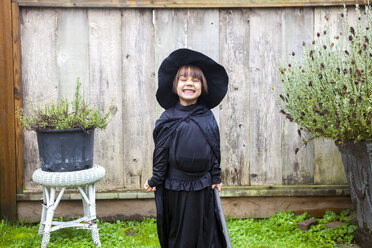 Portrait enthusiastic girl wearing witch costume in garden - CAIF05457