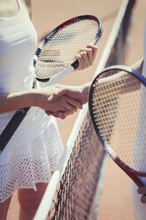 Tennisspieler schütteln sich sportlich die Hände am Netz auf einem sonnigen Tennisplatz - CAIF05487