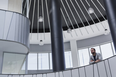 Nachdenklicher Geschäftsmann auf architektonischem, modernem Atrium-Balkon - CAIF05508