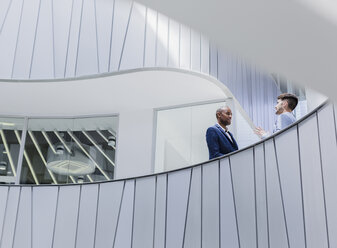 Businessmen talking on architectural, modern office balcony - CAIF05509