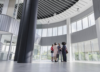 Business people talking in architectural, modern office lobby - CAIF05522