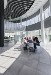 Geschäftsleute treffen sich an einem Tisch in einem modernen Büro-Atrium - CAIF05523