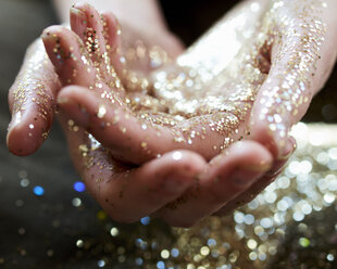 Nahaufnahme Hände, die Goldglitter schröpfen - CAIF05537